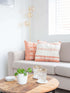 A cozy living room featuring a comfortable couch with pink & white pillow covers, a stylish coffee table, and a dining table for gatherings.