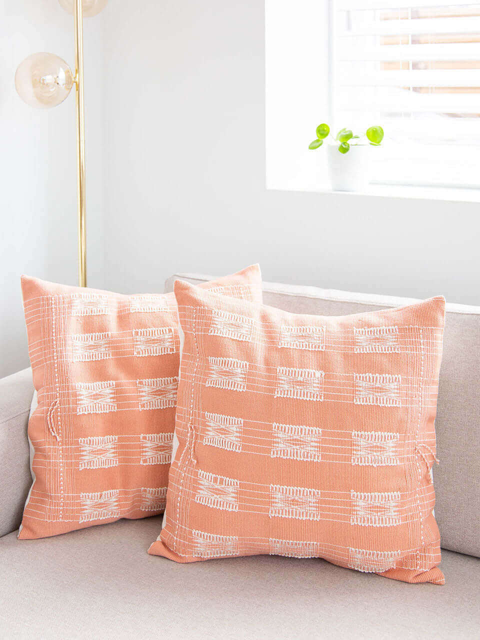 Two pink pillow covers with white geometrical patterns resting on a couch, adding a touch of style and comfort to the living space.