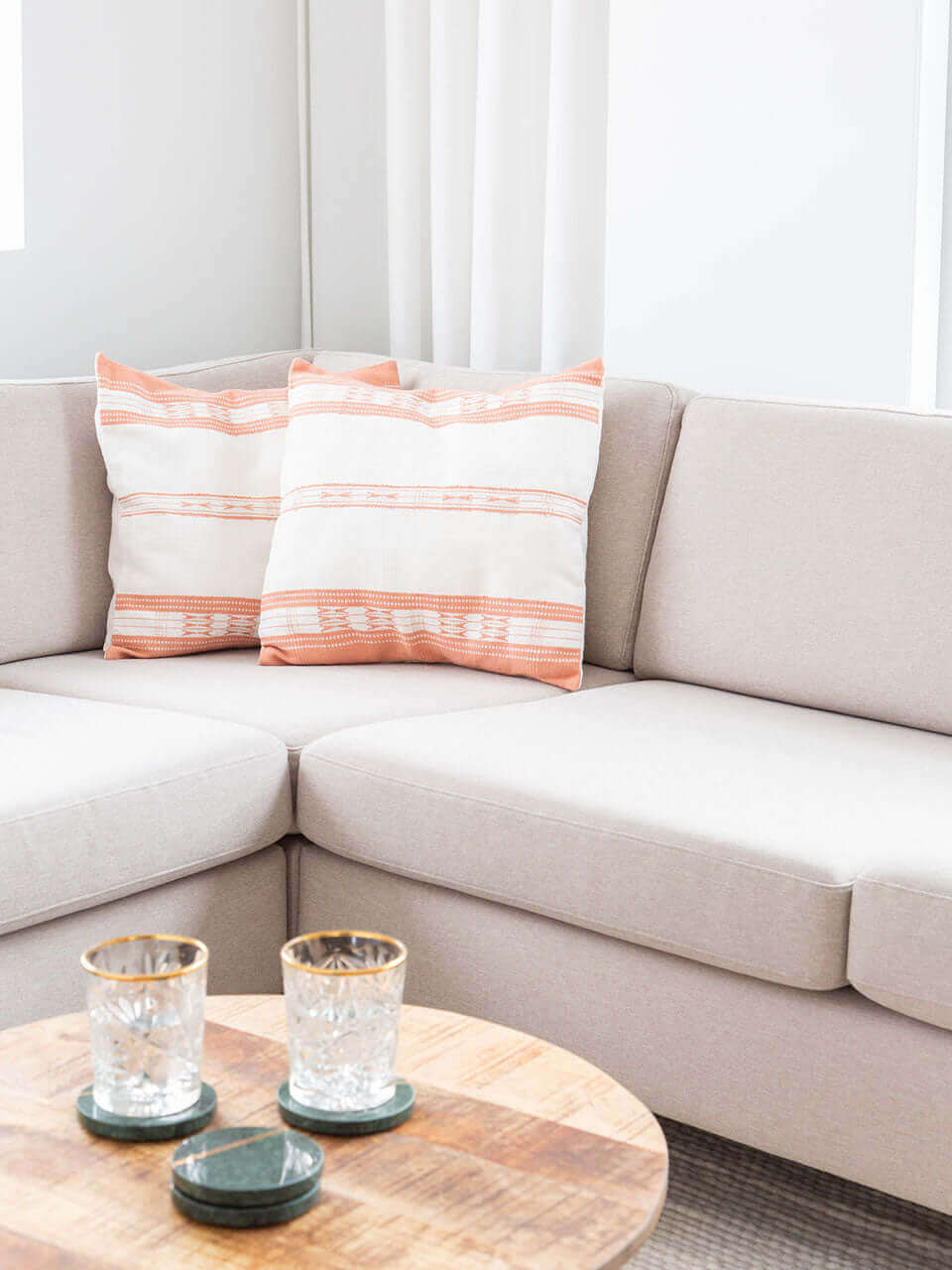 A cozy living room featuring a comfortable couch with pink & white pillow covers, a stylish coffee table, and a dining table for gatherings.