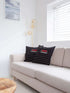 Two black pillow cover featuring bold red and white stripes, arranged side by side on a neutral background.