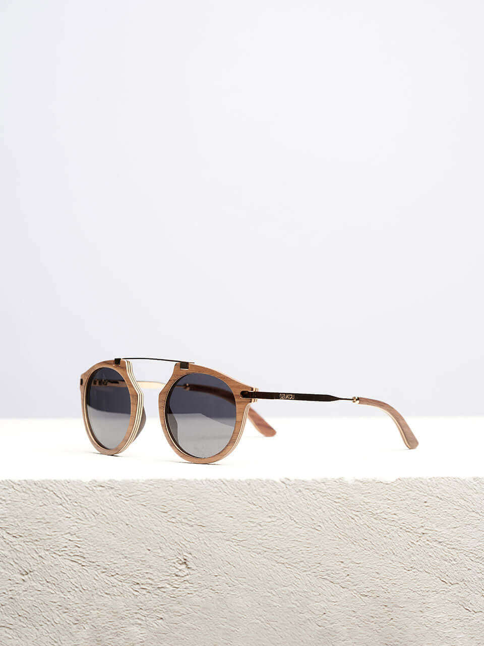 A wooden sunglasses featuring a stylish wooden frame in a clean surface with a neutral background, showcasing a unique and eco-friendly design.