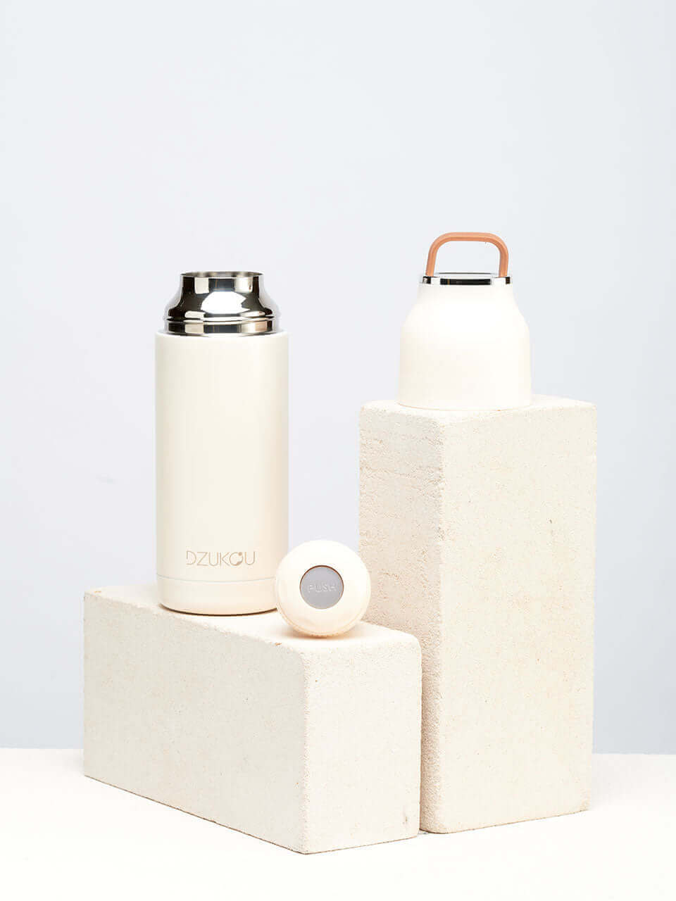 A white stainless steel water bottle placed next to a brick on a white background.