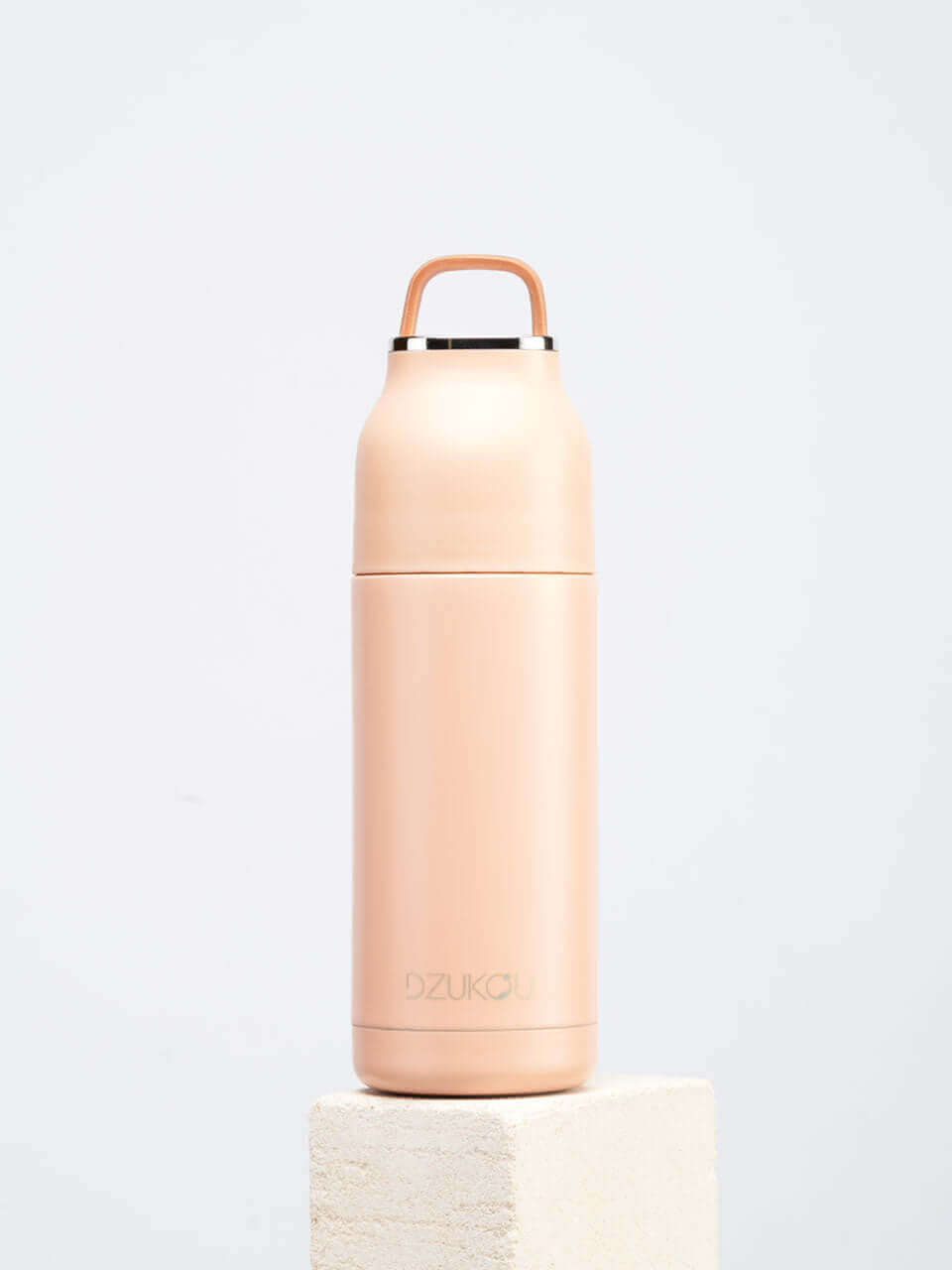 A peach water bottle featuring a handle, showcasing a blend of modern and natural design elements.