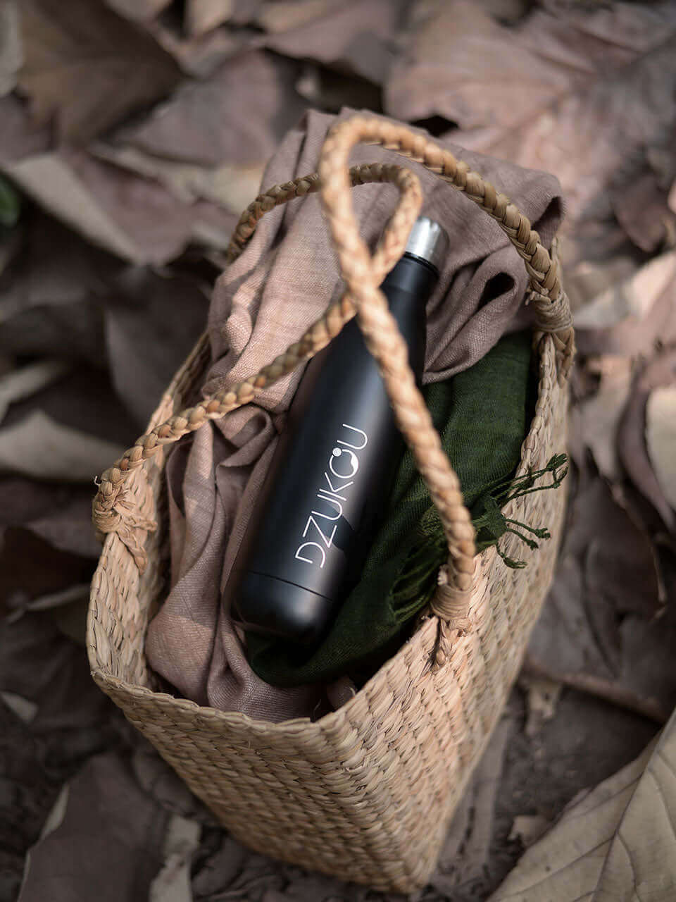 A black water bottle placed inside a woven wicker basket, showcasing a blend of functionality and natural aesthetics.
