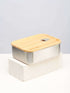 A bamboo lunch box with a vacuum seal on top of a white block, designed for secure storage.