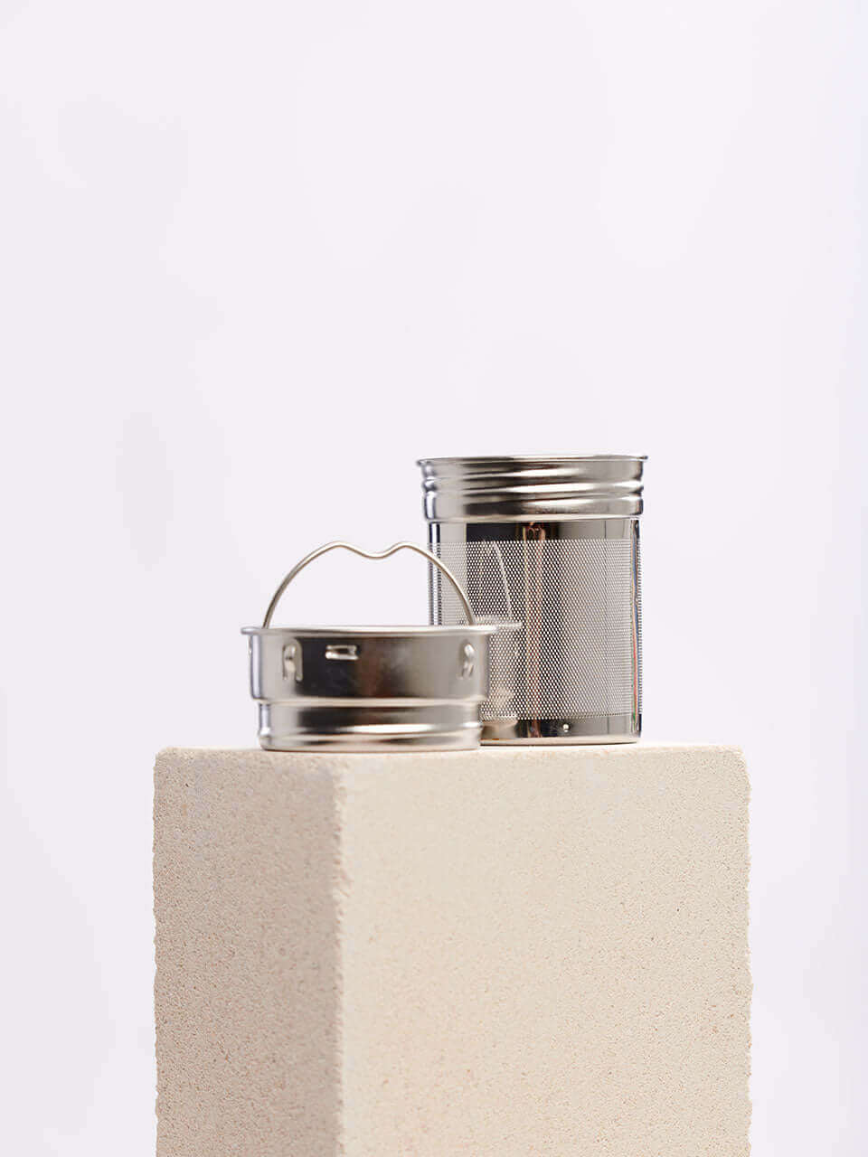 A metal container with a lid alongside a metal canister, both showcasing a sleek and industrial design.