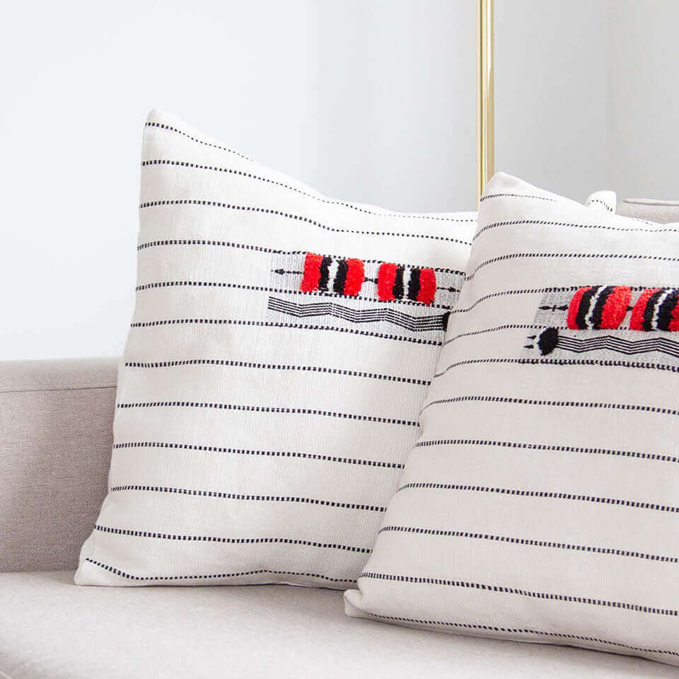 Two white pillow cover featuring bold red and black stripes, arranged side by side on a neutral background.