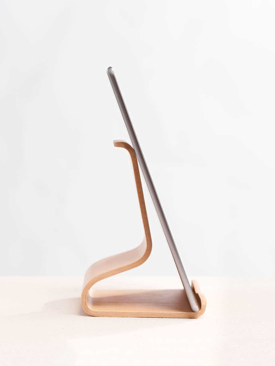 A side view of the tablet stand placed on a clean white surface, showcasing a blend of technology and natural materials.