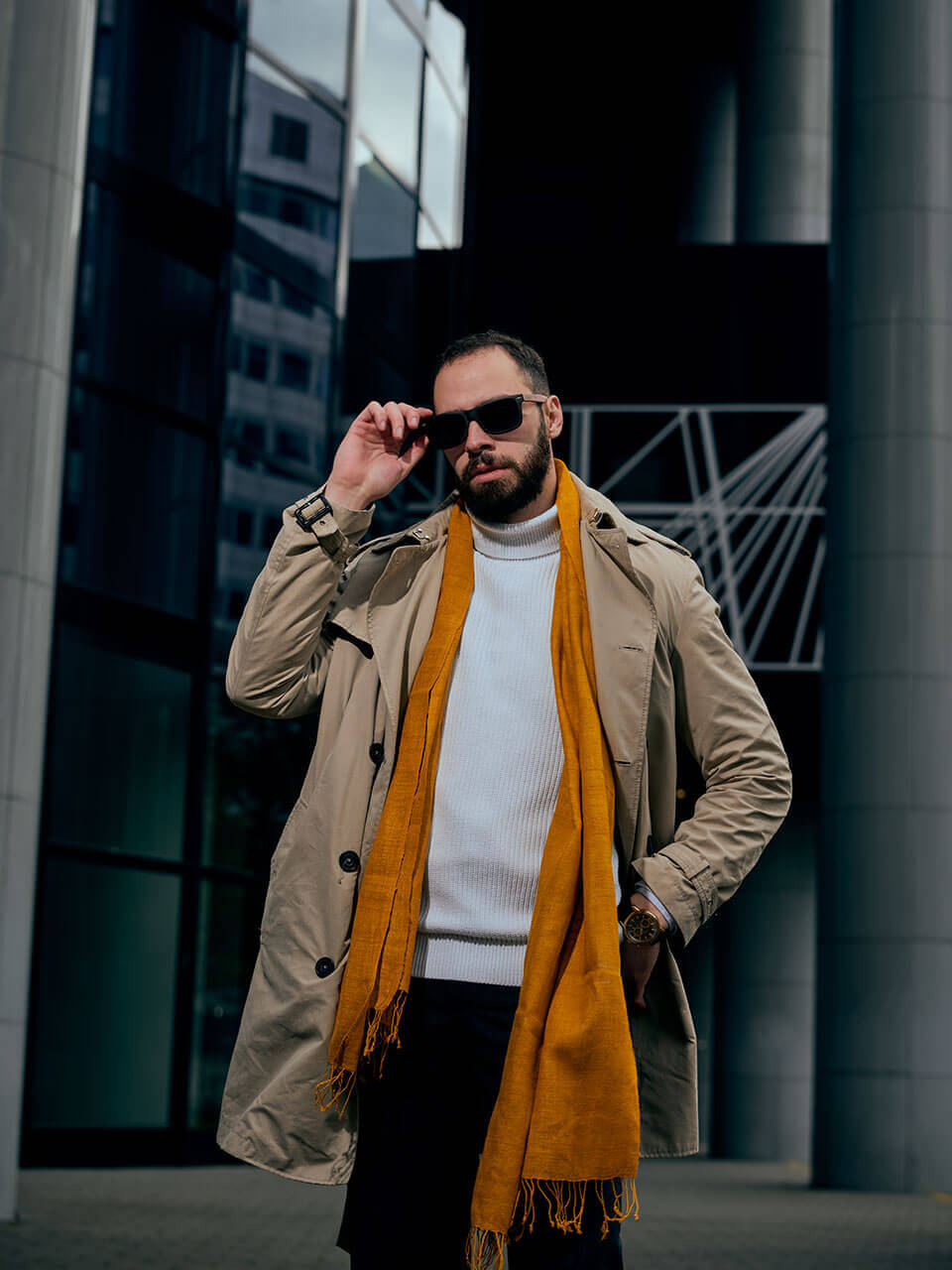 A man in sunglasses and a mustard scarf, exuding a stylish and confident demeanor.
