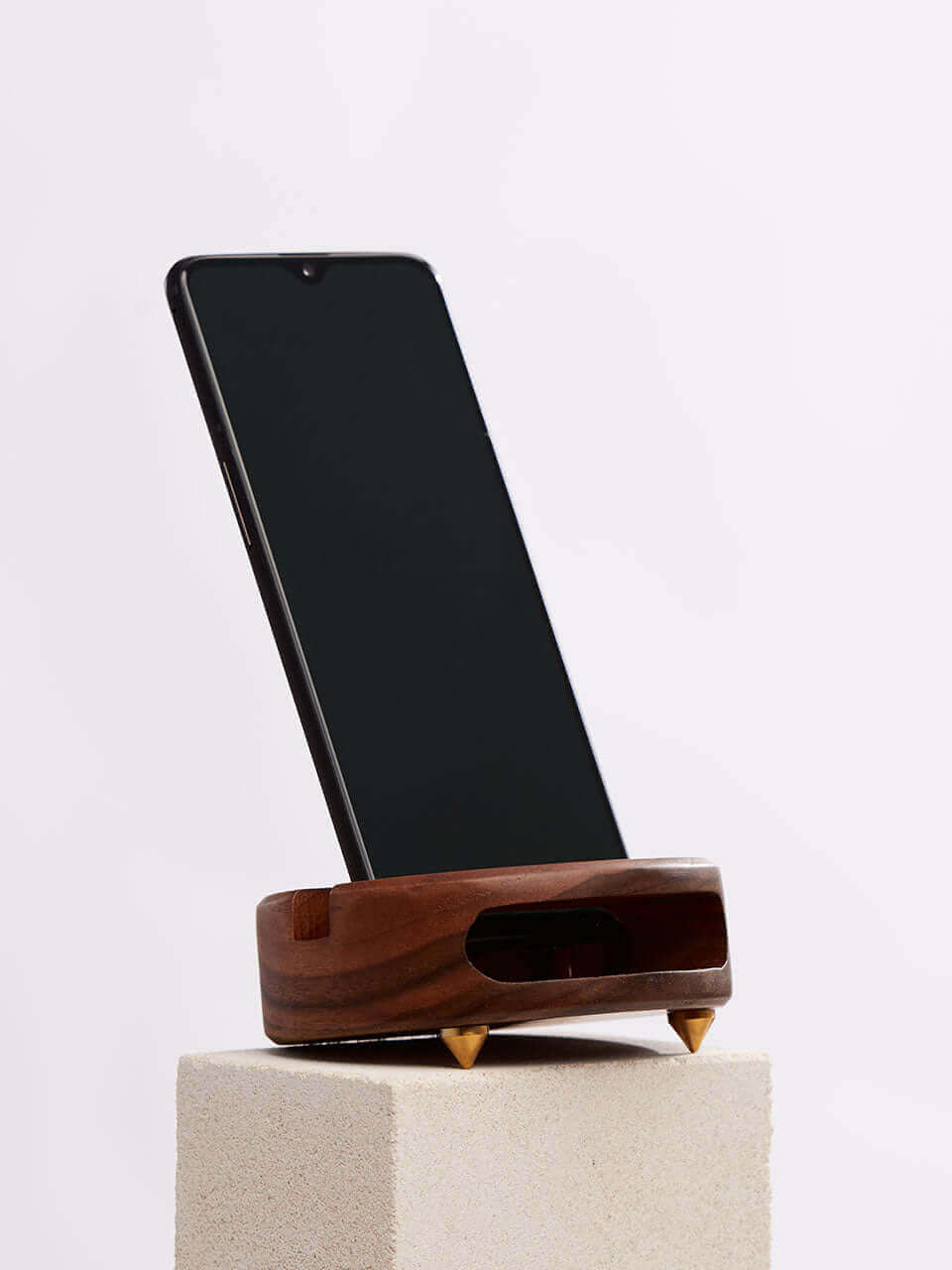 A cell phone placed on a white block, showcasing a blend of technology and natural materials.