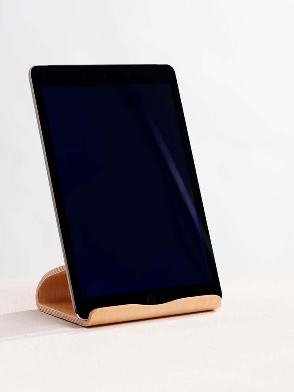 A tablet stand placed on a clean white surface, showcasing a blend of technology and natural materials.