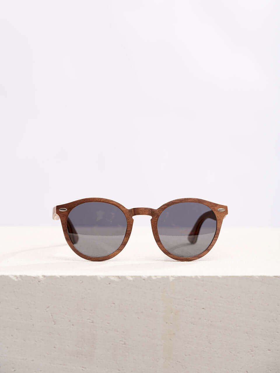 Wooden sunglasses with dark lenses in a neutral background, showcasing a unique and eco-friendly design. Perfect for stylish sun protection.