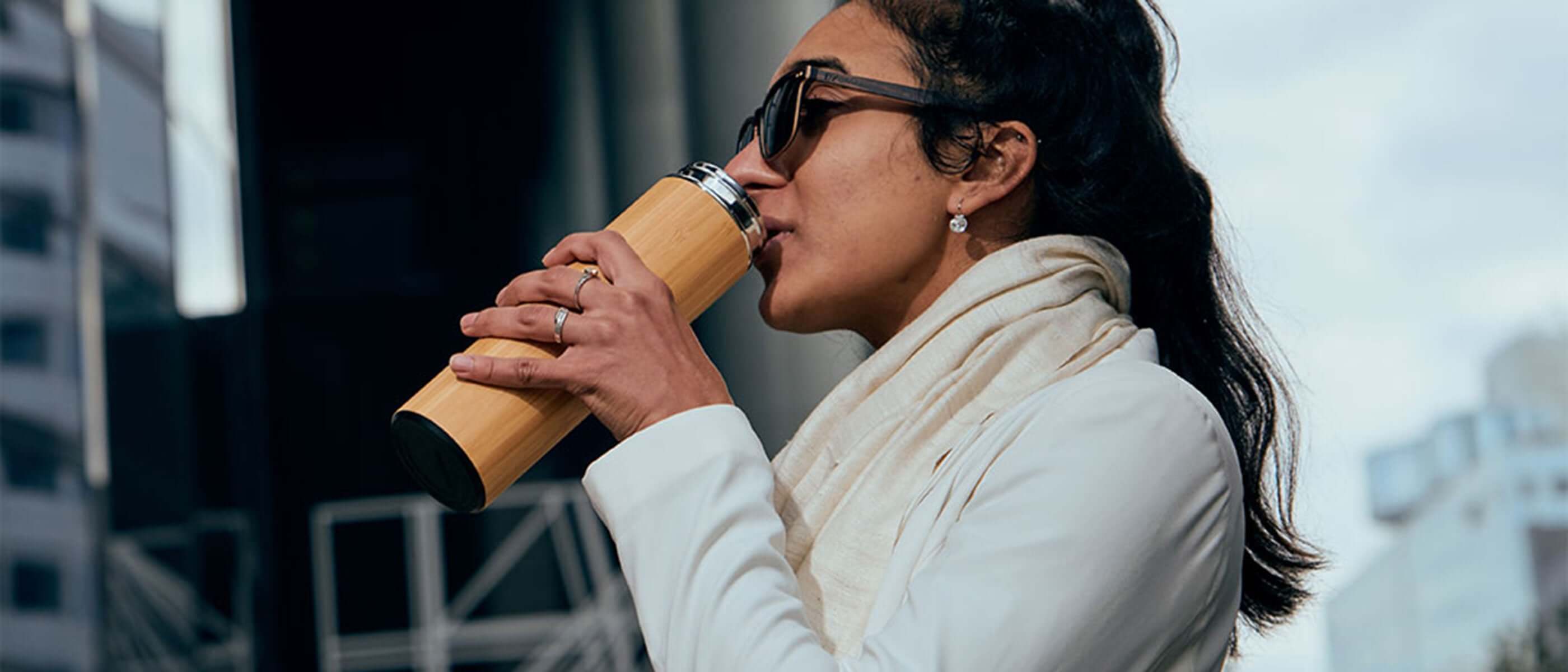 woman drinking water from a bamboo water bottle
