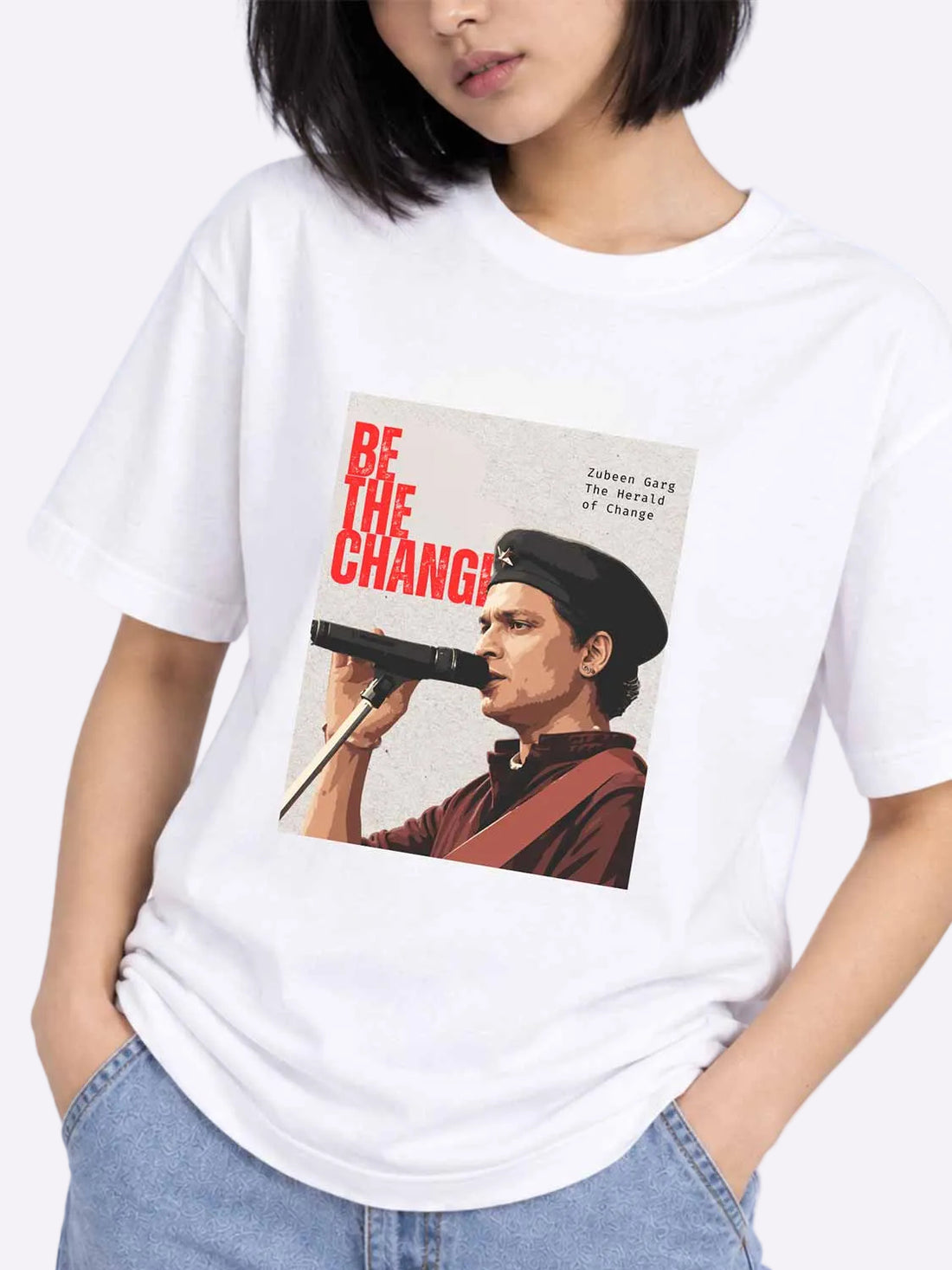 A woman wearing a white short-sleeve graphic T-shirt with a vintage-style print of a man speaking into a microphone and the text &