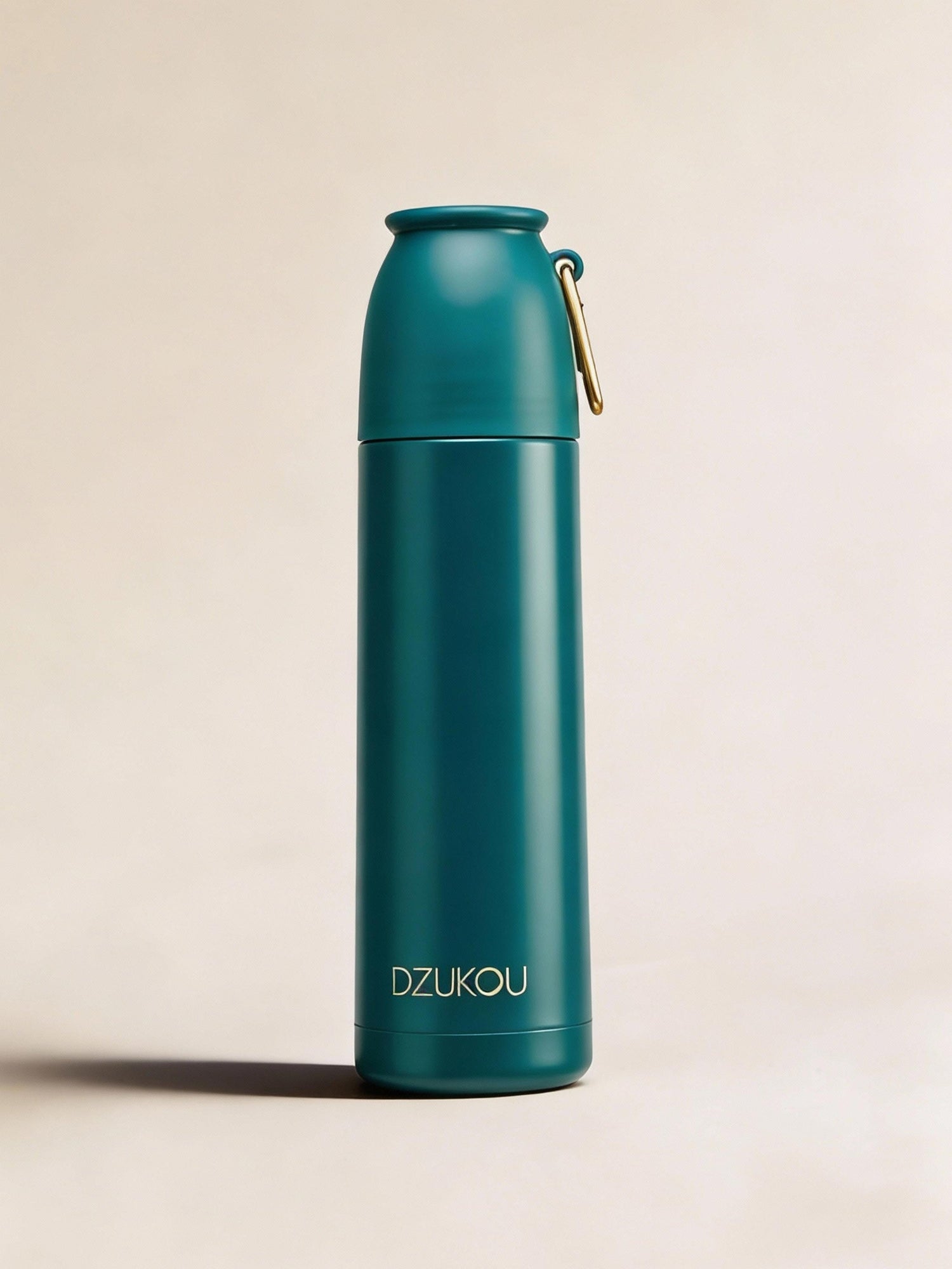 Teal water bottle with gold cap on a beige background