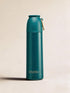 Teal water bottle with gold cap on a beige background