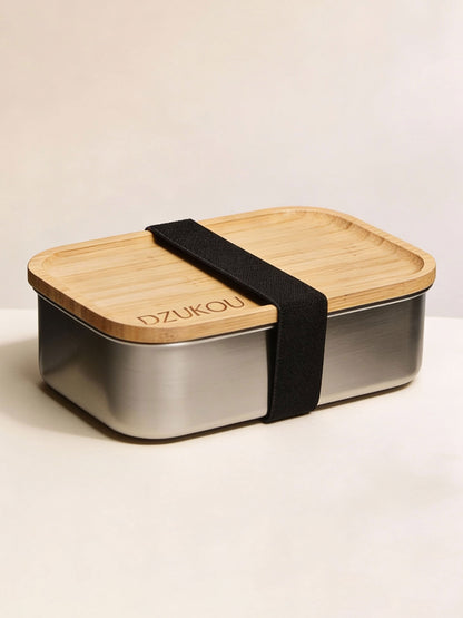 Bento box with wooden lid and metal body on a beige background
