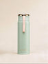 Mint green thermos with pink strap on a beige background