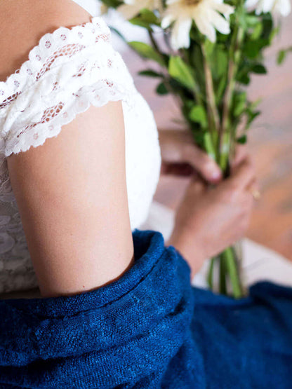 A woman draped in a soft, elegant blue Eri silk shawl, showcasing its smooth texture and natural color.