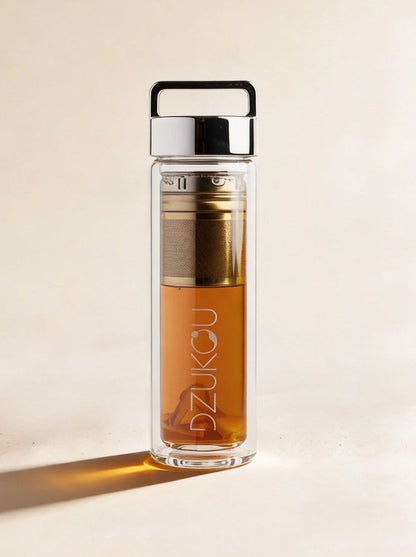 Clear glass bottle with metal cap and visible brand name on a beige background