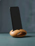 Wooden phone stand holding a smartphone on a gray background
