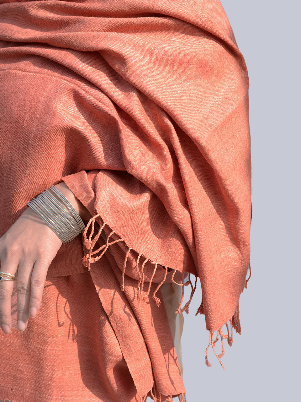 A woman draped in a soft, elegant peach stole, showcasing its smooth texture and natural color.