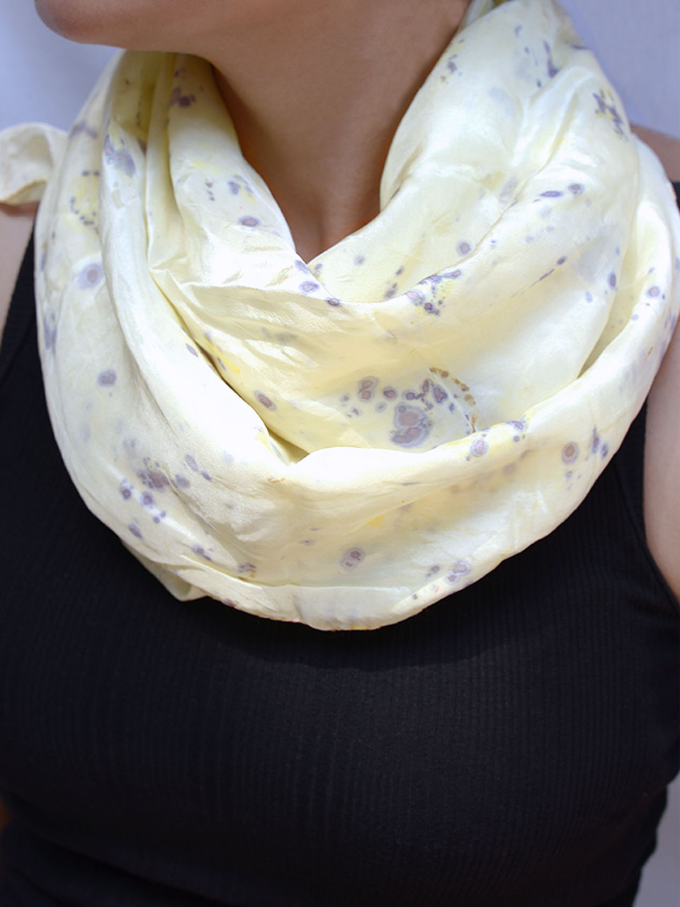 A woman adorned in a white scarf featuring purple-blue pattern, exuding a vibrant and cheerful appearance