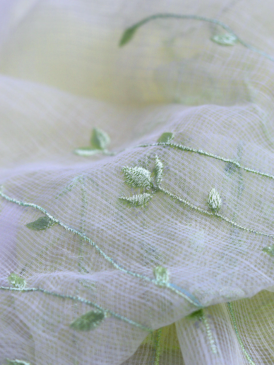 Green fabric adorned with intricate yellow embroidery, showcasing a delicate and elegant design.