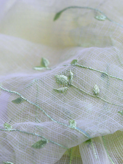 Green fabric adorned with intricate yellow embroidery, showcasing a delicate and elegant design.