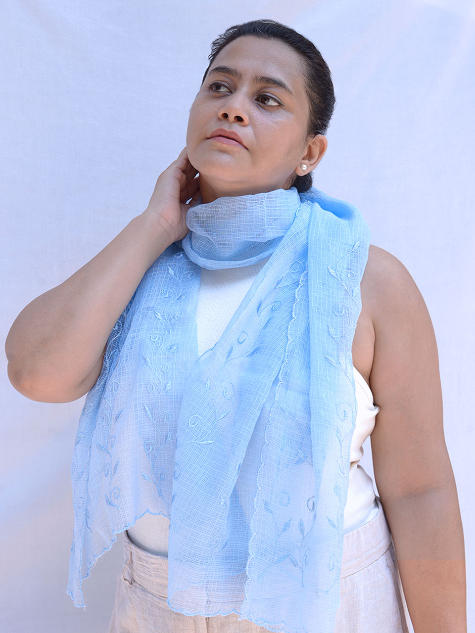 A woman elegantly draped in a light blue scarf, exuding grace and style.