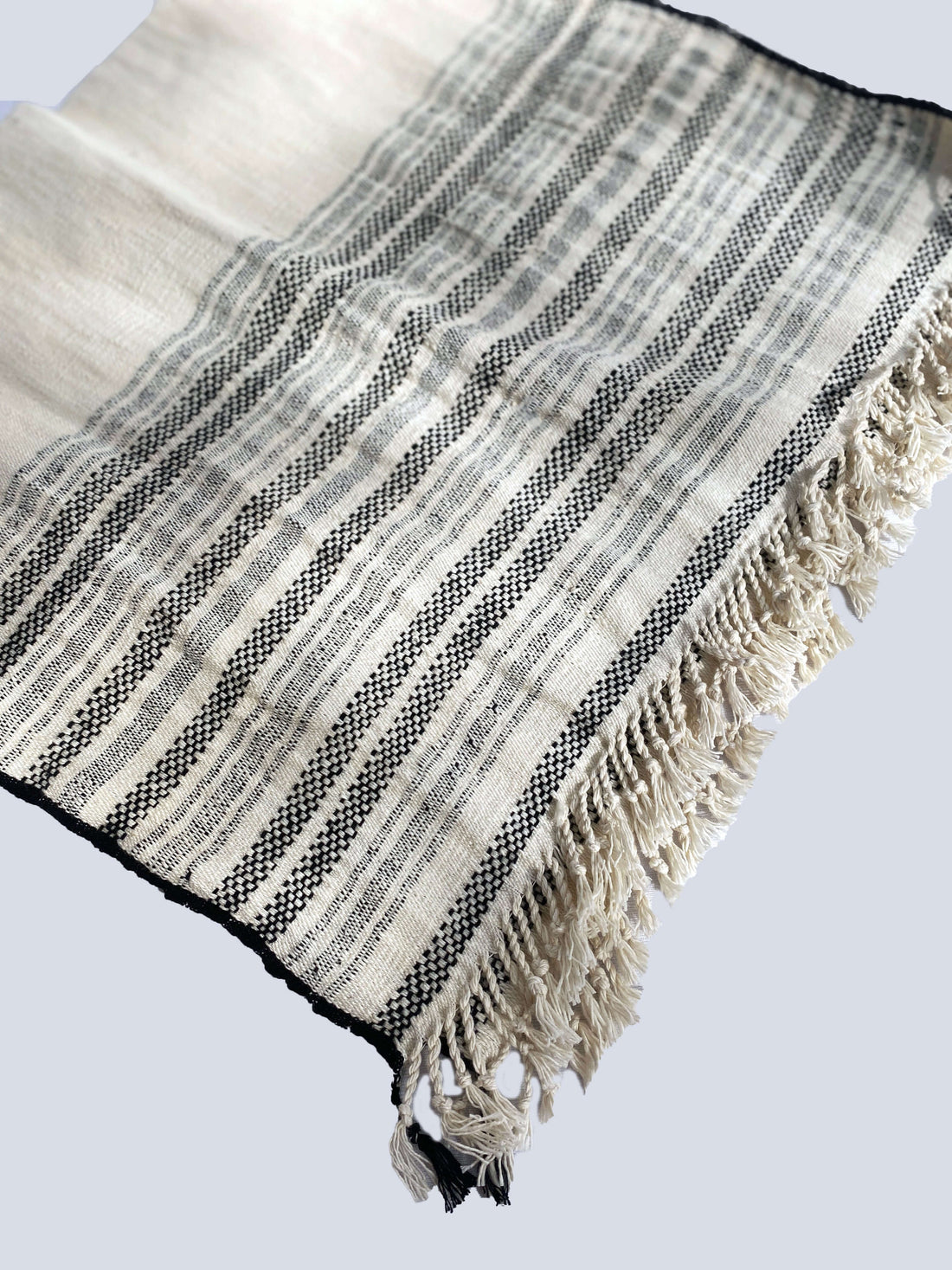 A white and black striped organic cotton hand towel with fringes, showcasing a stylish and textured design.