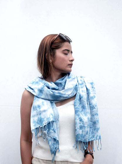 A woman elegantly draped in a blue tie-dye scarf, showcasing vibrant patterns and a stylish appearance