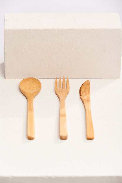 A set of three wooden spoons and forks arranged neatly on a light background