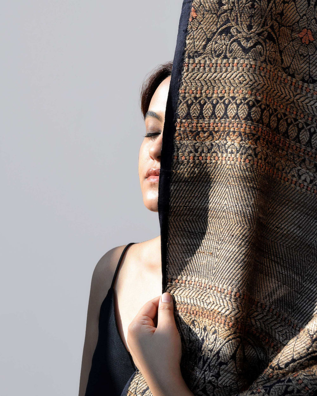 A woman holds a large piece of fabric, showcasing its texture and color in a well-lit environment.