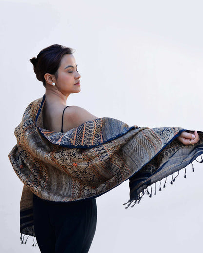 A woman elegantly draped in a patterned shawl, showcasing intricate designs and vibrant colors.