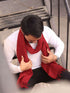 A man in a red scarf is seated on a bench, enjoying a moment of relaxation outdoors.