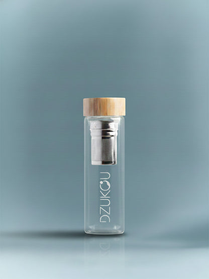Clear glass bottle with wooden cap and metal filter on a gray background