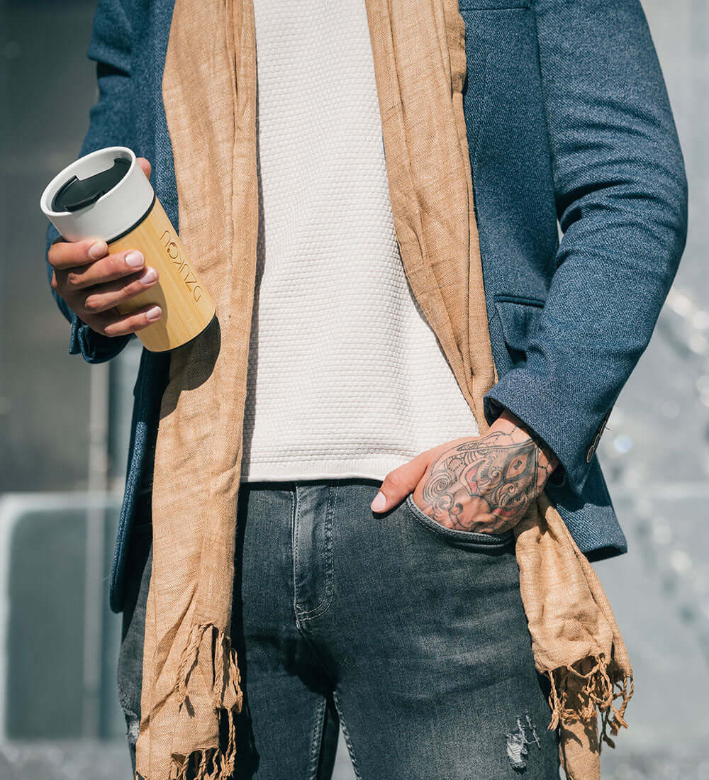 a man with a tattoo on his hand holding a coffee tumbler