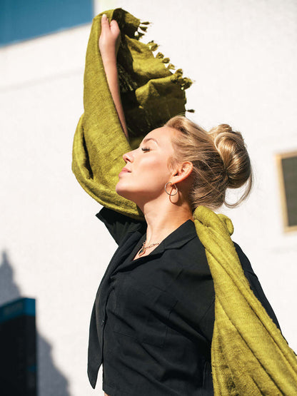 A woman draped in a soft, elegant olive Eri silk shawl, showcasing its smooth texture and natural color.