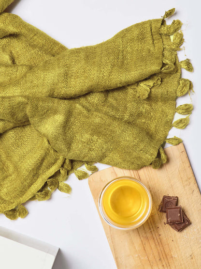 An olive Eri silk shawl spread out on a surface, highlighting its soft texture and natural color.