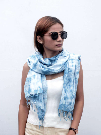 A woman elegantly draped in a blue tie-dye scarf, showcasing vibrant patterns and a stylish appearance