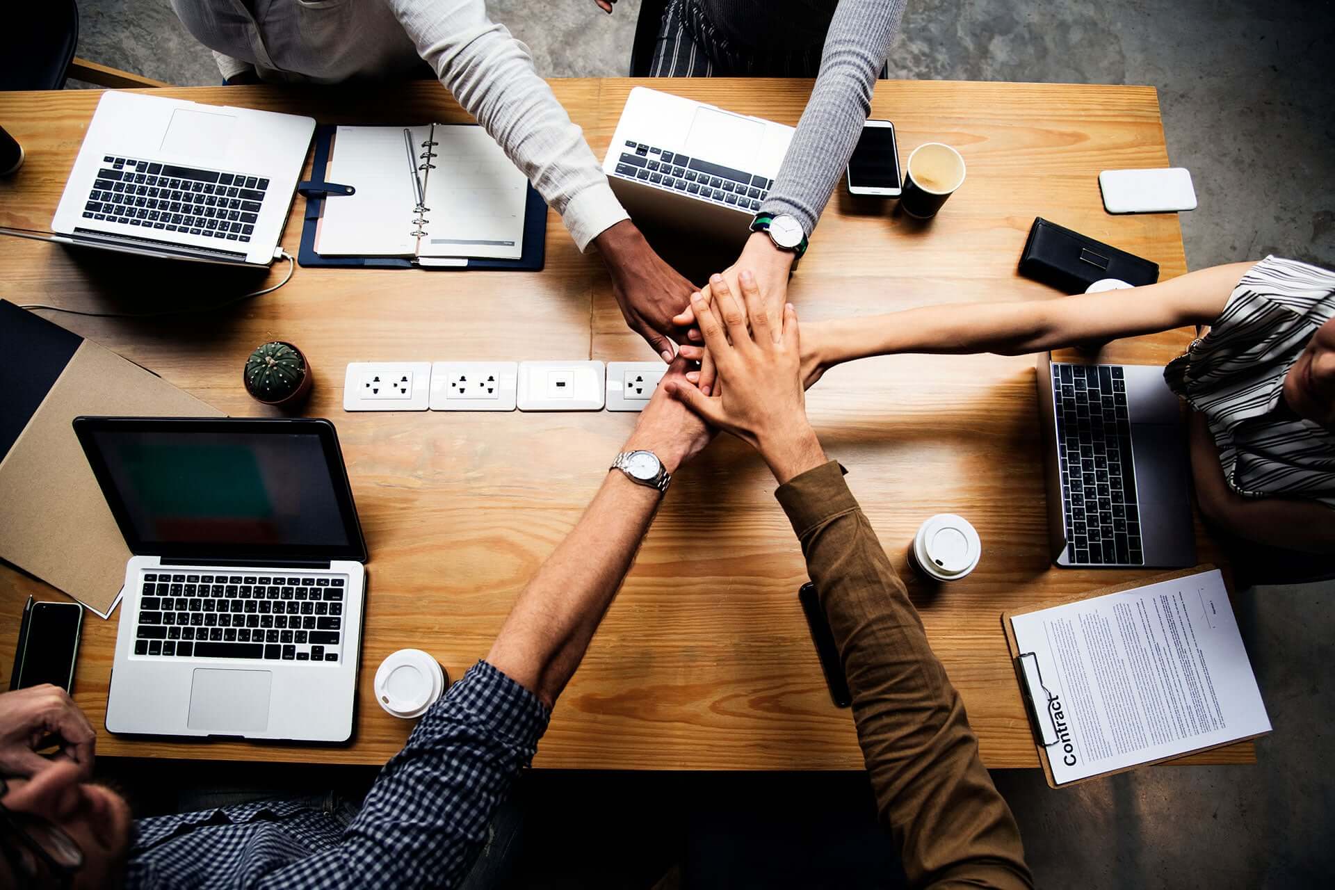 people joining hands over office desk