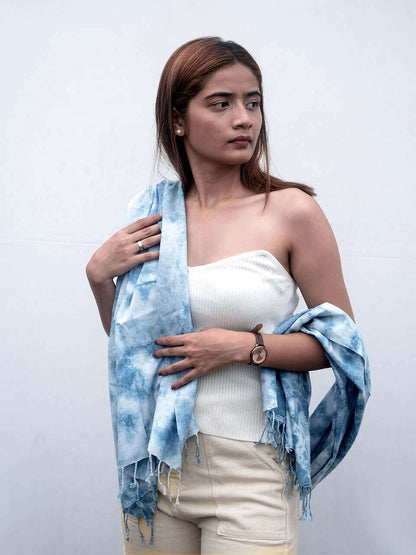 A woman elegantly draped in a blue tie-dye scarf, showcasing vibrant patterns and a stylish appearance