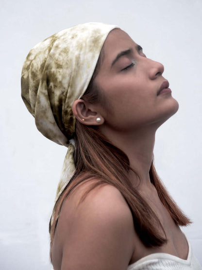 A woman with her eyes closed, wearing a head scarf, exudes tranquility and serenity in a peaceful moment.