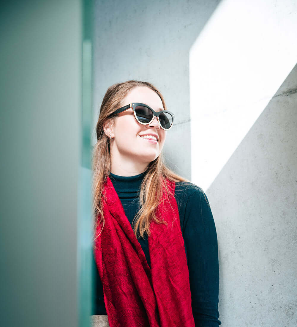 a girl wearing red stole with her sunglasses on.