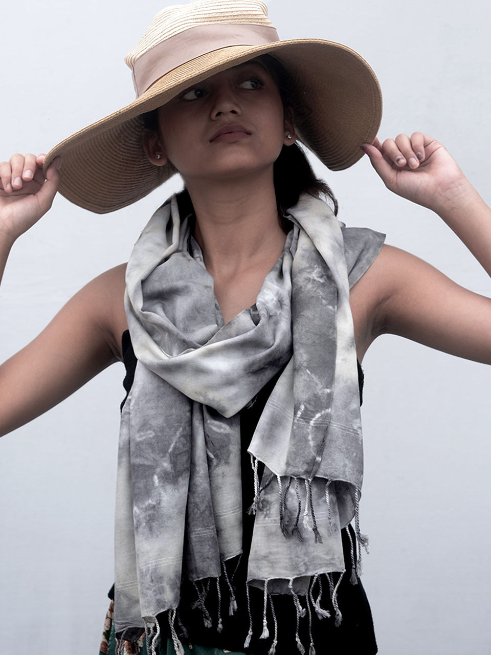 A woman elegantly dressed in a hat and grey scarf, showcasing a stylish winter look