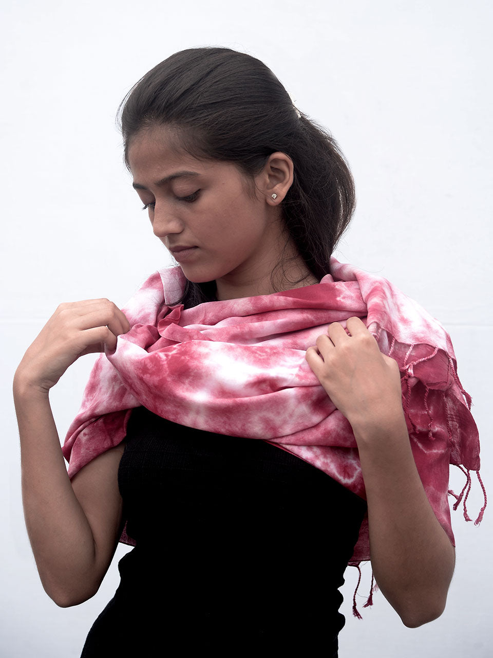 A woman elegantly draped in a vibrant red tie-dye scarf, showcasing a blend of colors and style