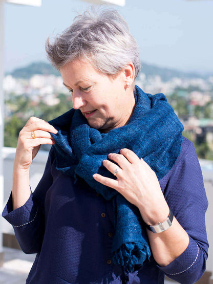 A woman draped in a soft, elegant blue Eri silk shawl, showcasing its smooth texture and natural color.