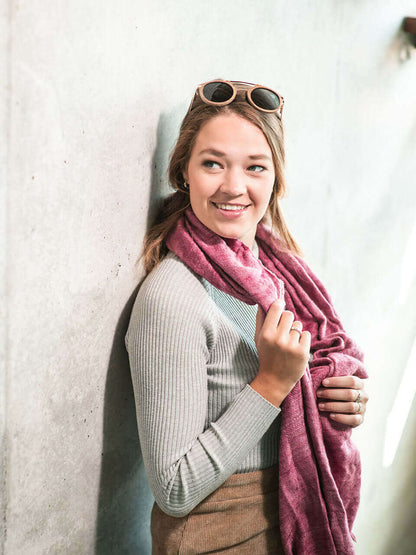 A woman draped in a soft, elegant pink Eri silk shawl, showcasing its smooth texture and natural color.