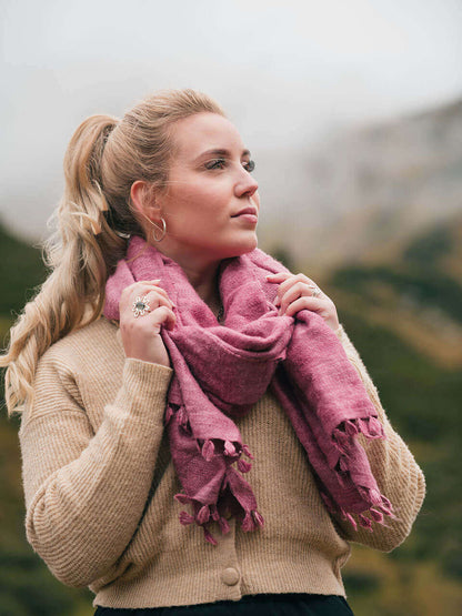 A woman draped in a soft, elegant pink Eri silk shawl, showcasing its smooth texture and natural color.